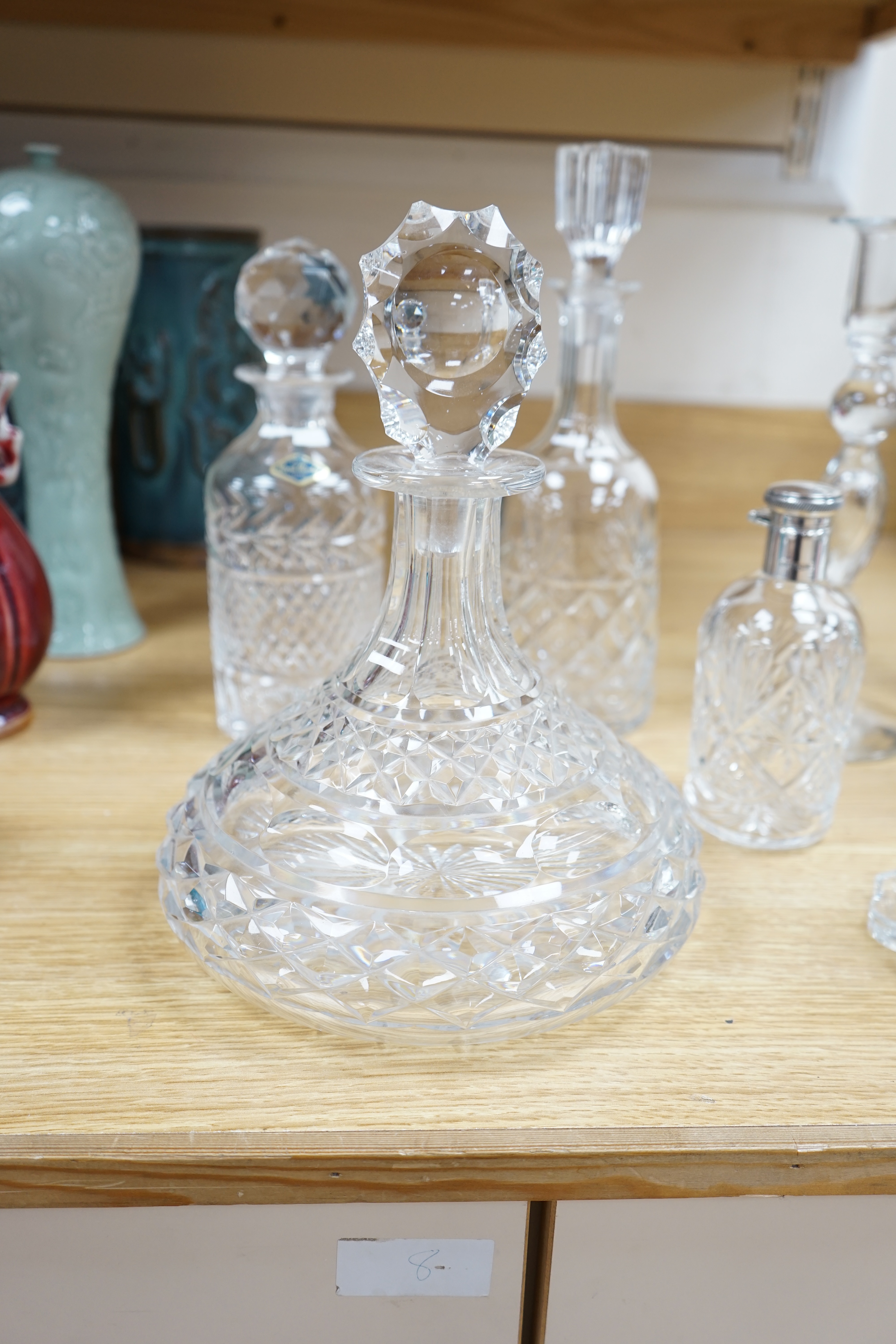 A cut glass ship’s decanter, two others and three various cut glass candle sticks, tallest decanter 30cm high. Condition - good